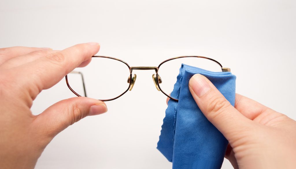 woman cleaning her glasses with microfiber cloth