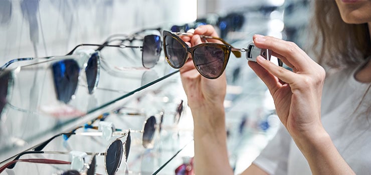 woman choosing sunglasses from display rack